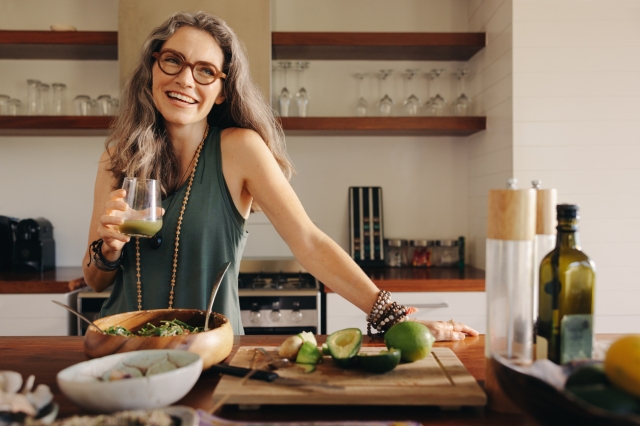 Woman making salad and drinking a healthy smoothie