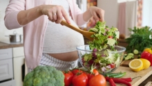 pregnant woman prepares salad