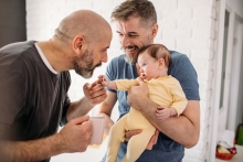 male couple holding their baby