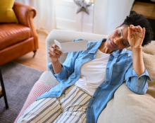 A woman lounging on the sofa and looking at some papers