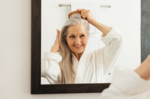 Image features an older woman looking at herself in the mirror